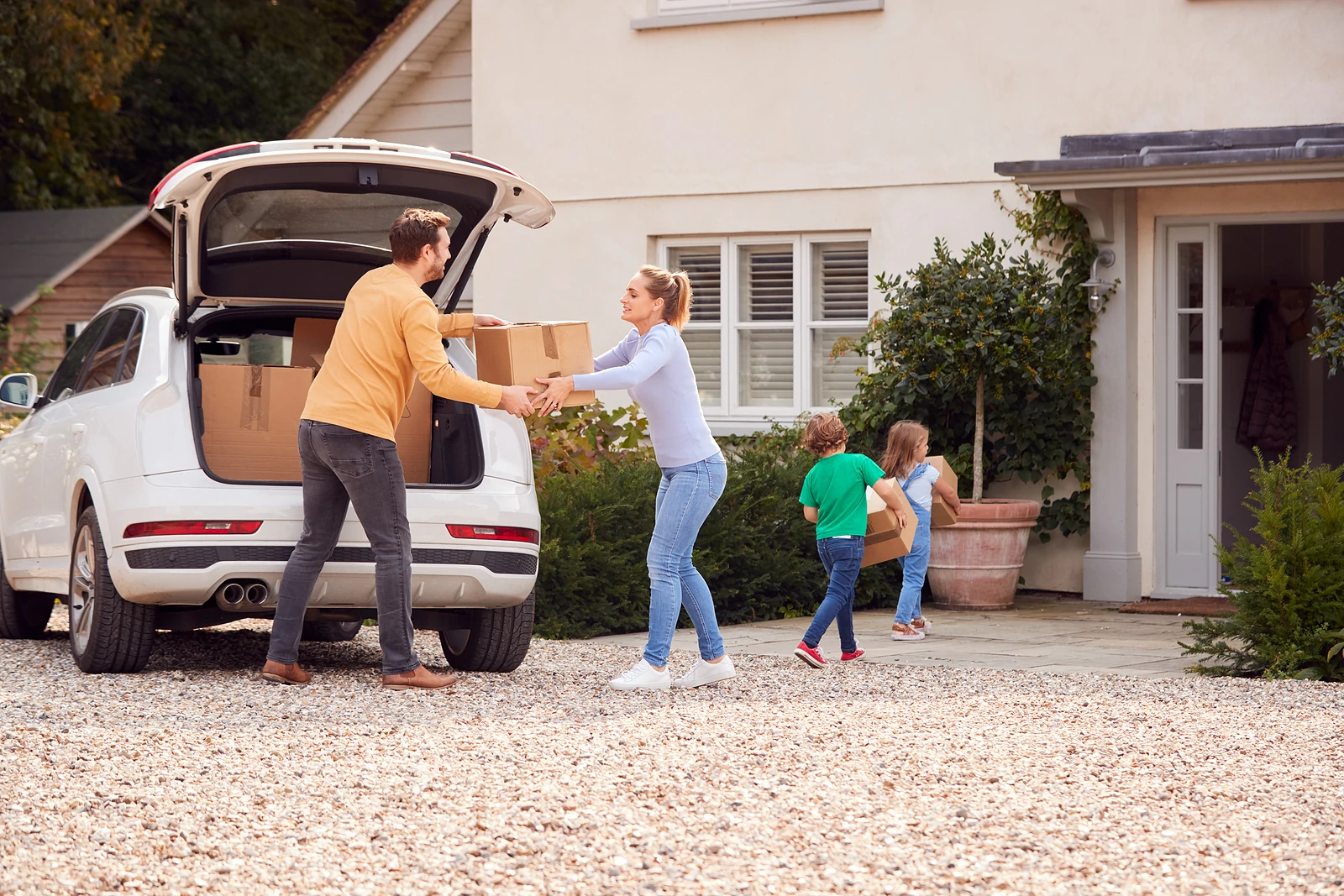 Family carrying boxes from car to new home
